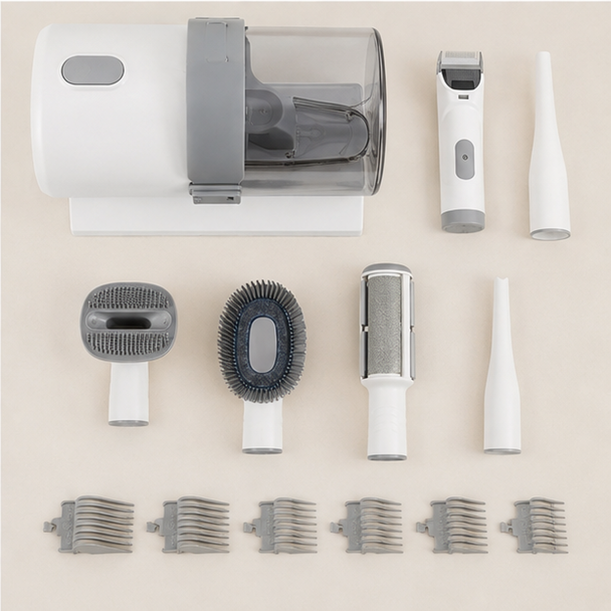 Complete pet grooming vacuum kit laid out: base unit with 2.5 litre clear container, hair clipper, crevice tool, four attachment heads and six clipping guide combs